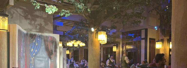 Dimly lit restaurant with branches of trees seeming to grow into the ceiling with lanterns providing a magical atmosphere.